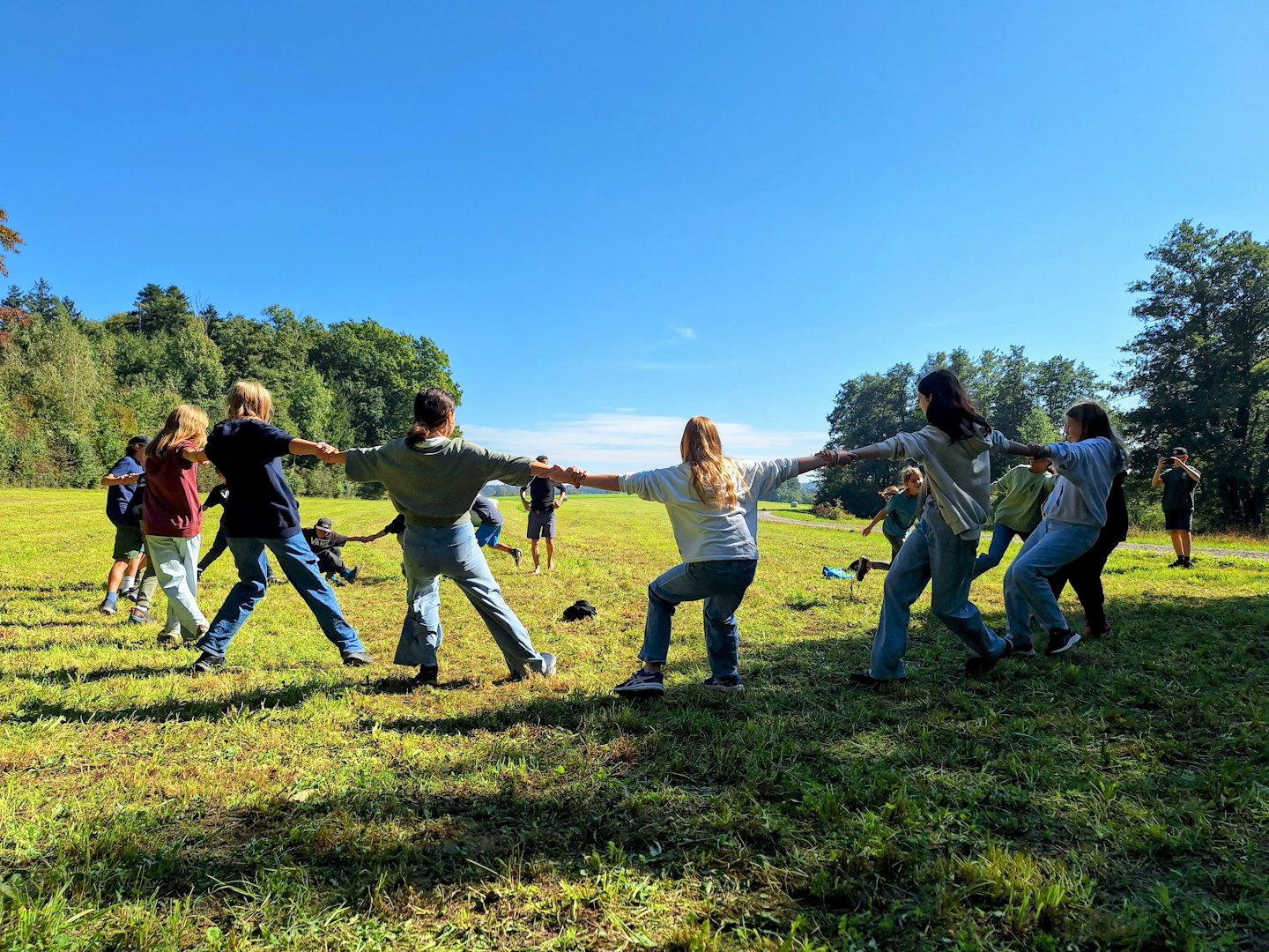 Eine Gruppe von Menschen hält sich in einem Grasfeld an den Händen.