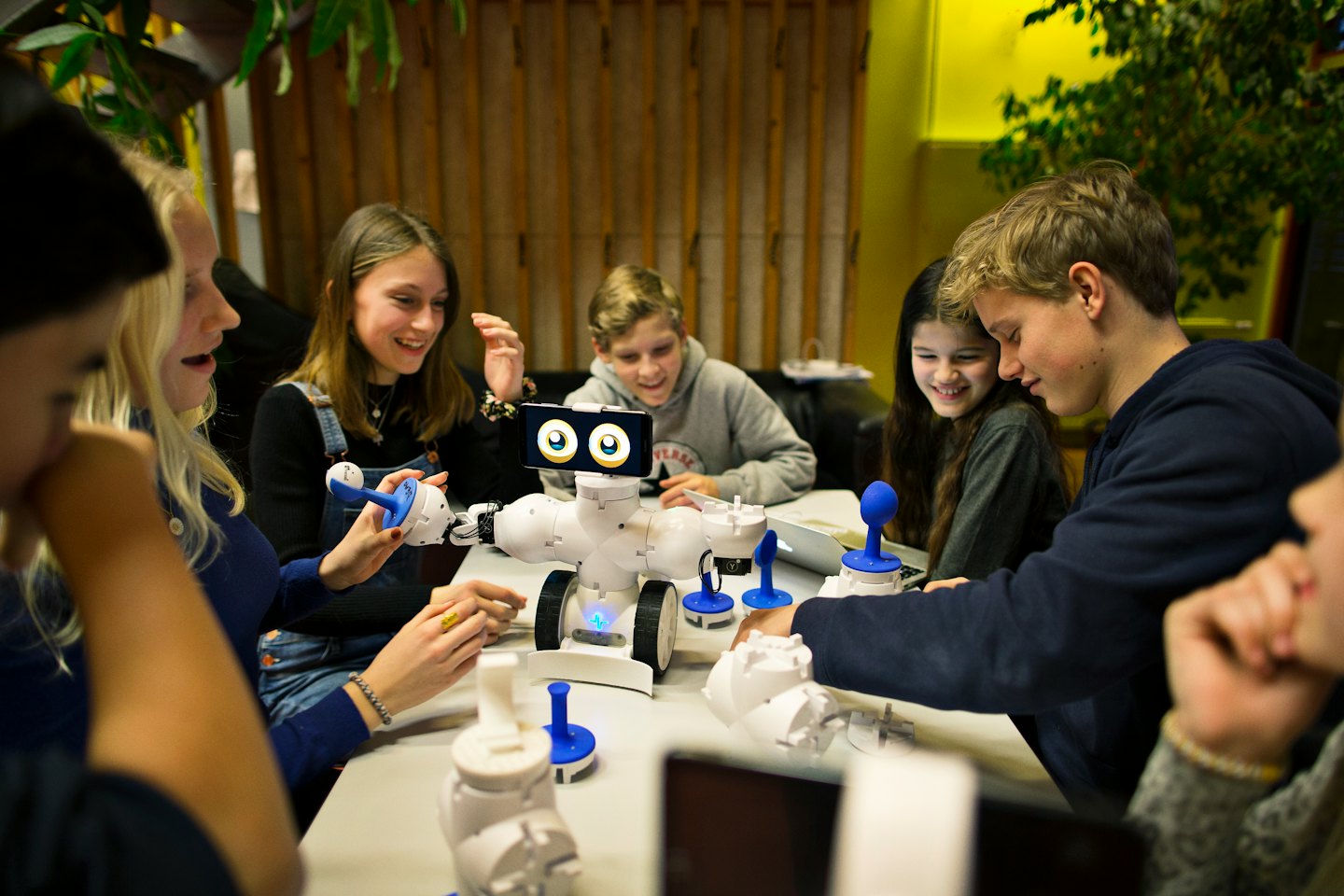 Jugendliche, die an einem Robotikprojekt an einem Tisch zusammenarbeiten.